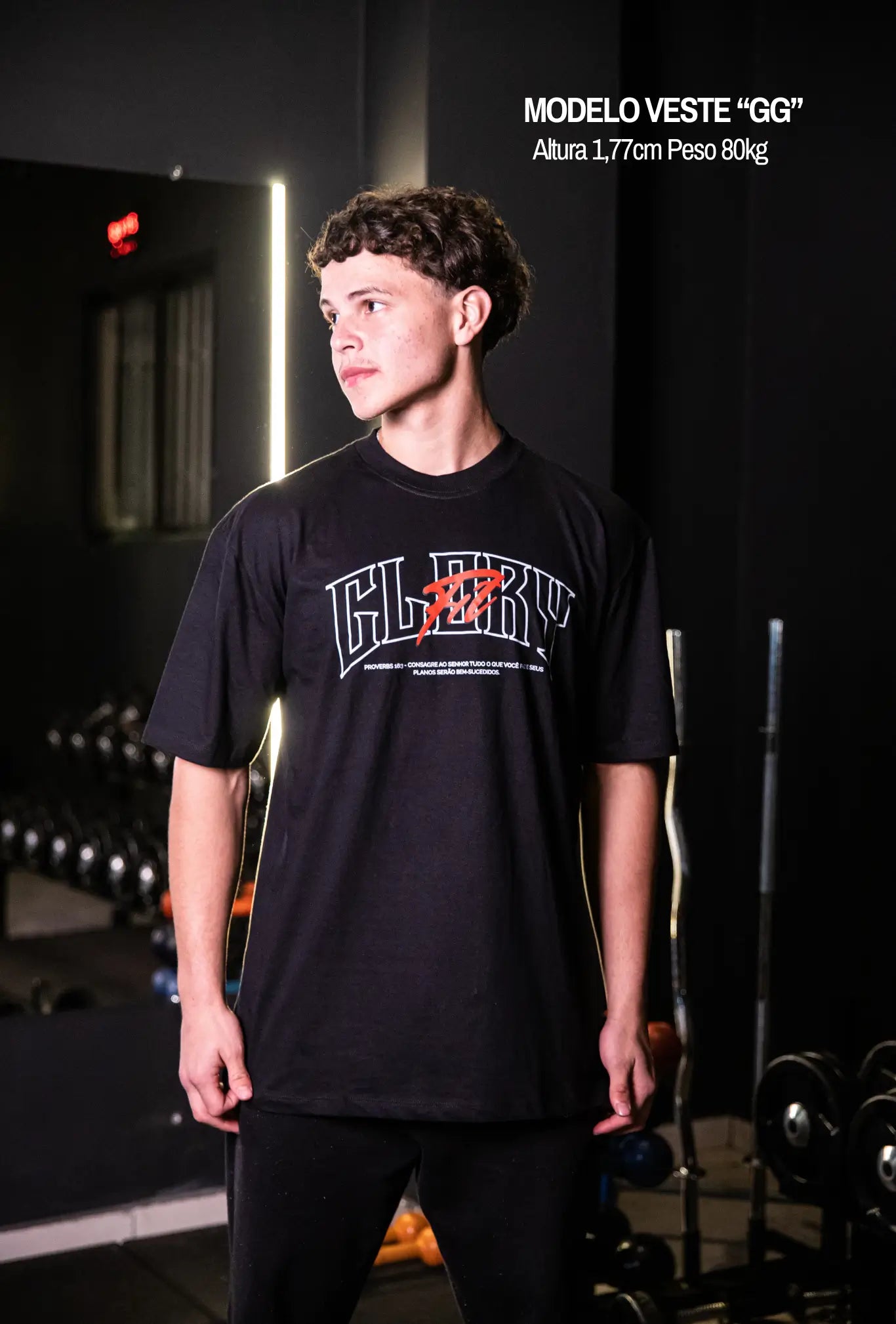 Camiseta oversized GLORYFIT preta vista frontal com modelo em ambiente de academia