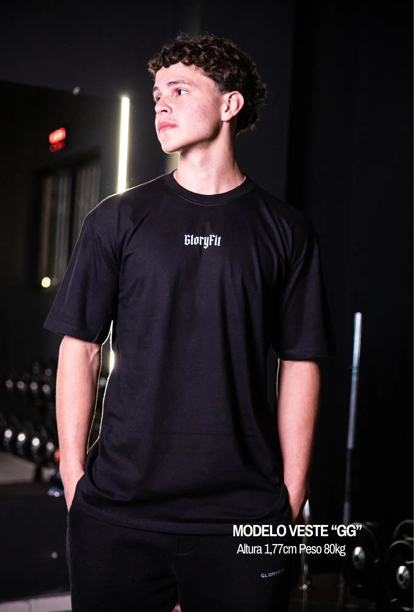 Camiseta oversized In God We Trust GLORYFIT preta vista frontal com modelo em ambiente de academia