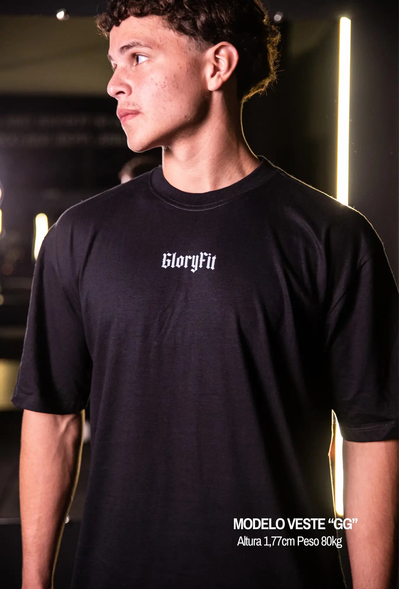 Camiseta oversized Man Of God GLORYFIT preta vista lateral frontal em ambiente de academia