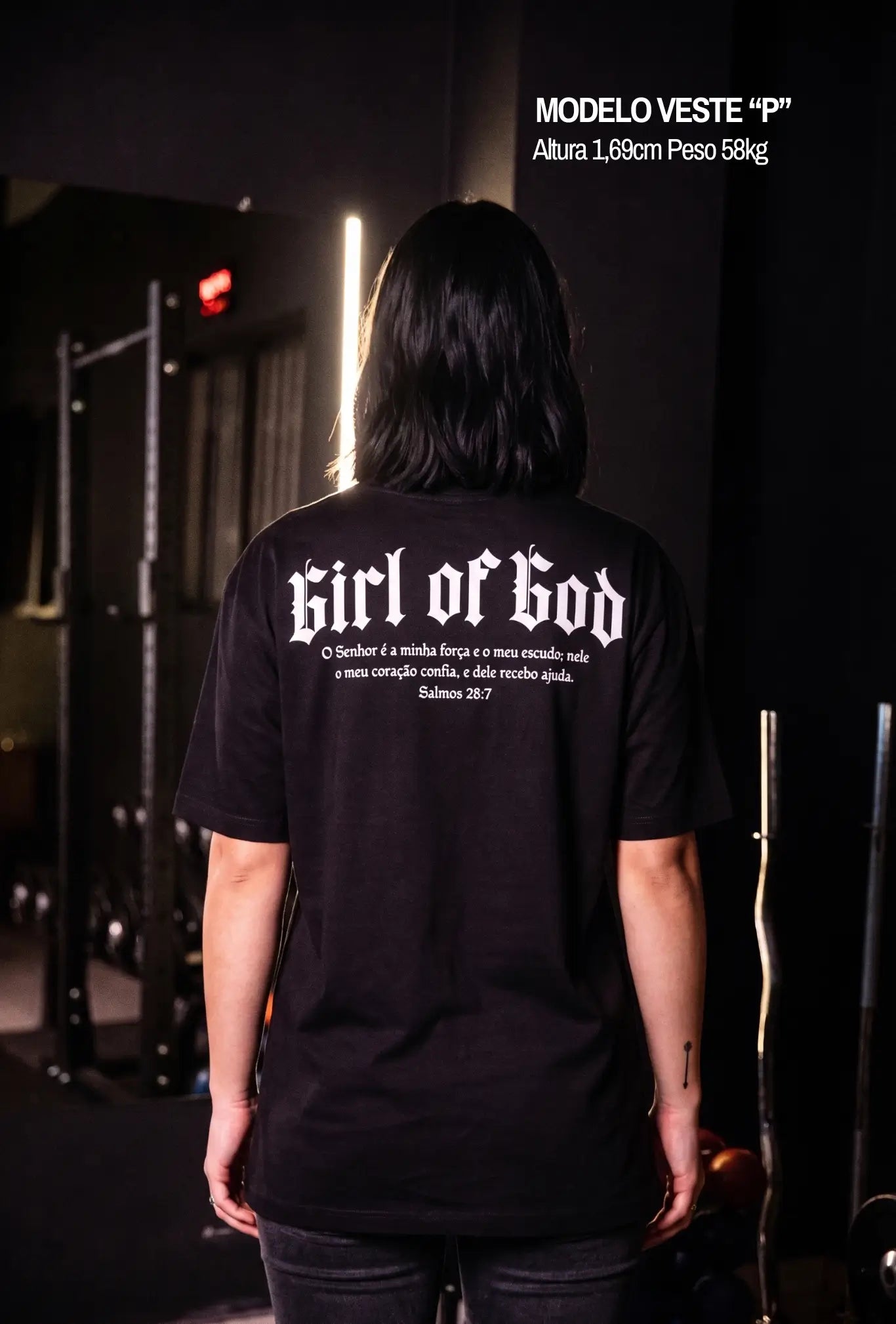 Modelo usando camiseta oversized preta Girl of God com versículo Salmos 28:7 nas costas