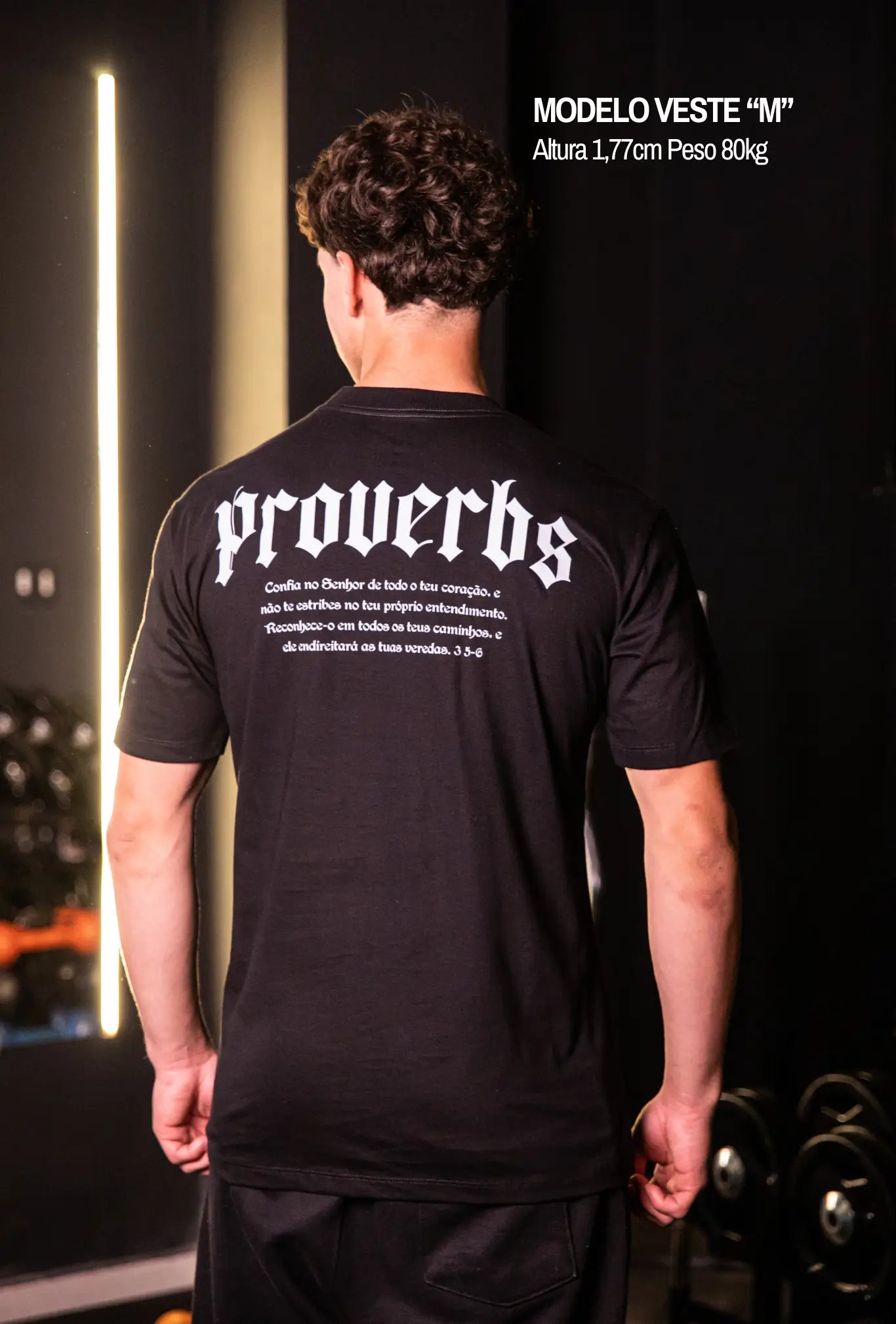 Camiseta oversized Proverbs GLORYFIT preta vista traseira em ambiente de academia